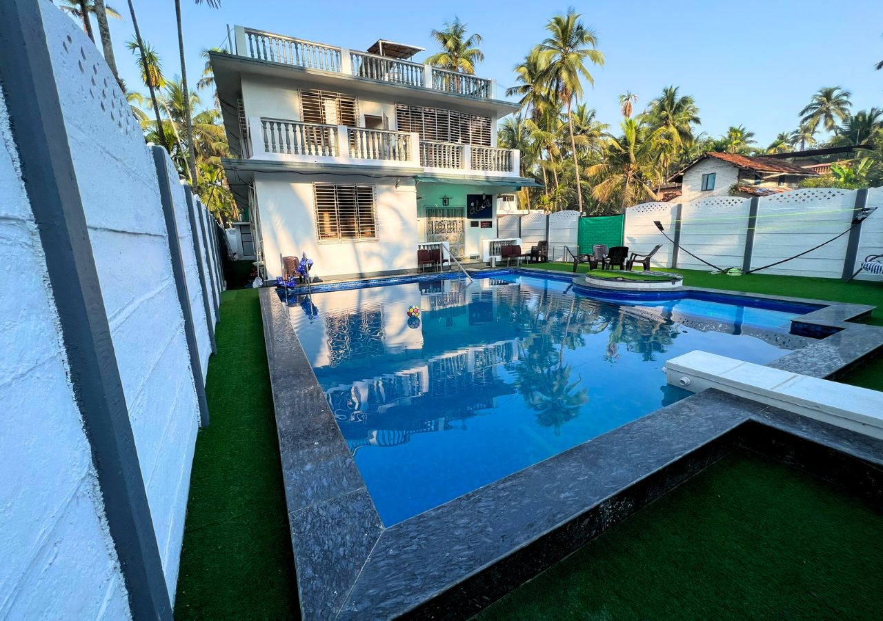 the pool view at vandana villa a 6 BHK villa in Alibag along with the badminton net and seating.