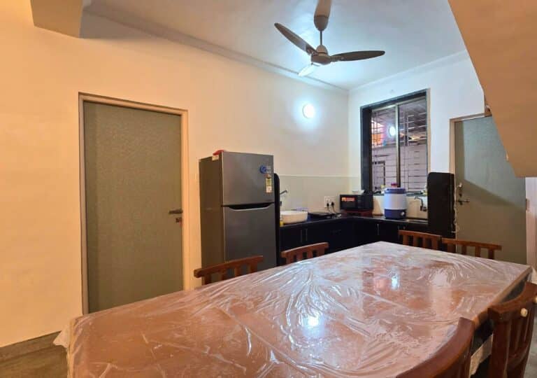 Vandana Villa, Alibag: Dining table beside the kitchen counter, with a fridge and microwave