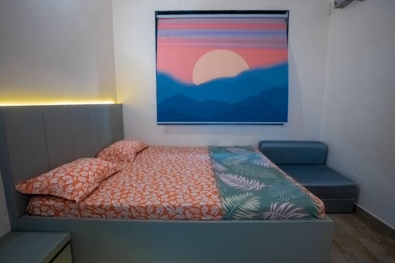 Vandana Villa, Alibag: AC bedroom with a bed, a sofa and a sunset print