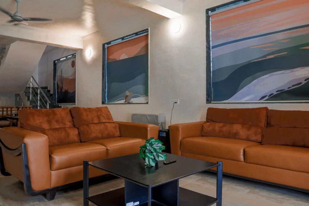 Vandana Villa, Alibag: Living hall with leather sofas and big sunset prints