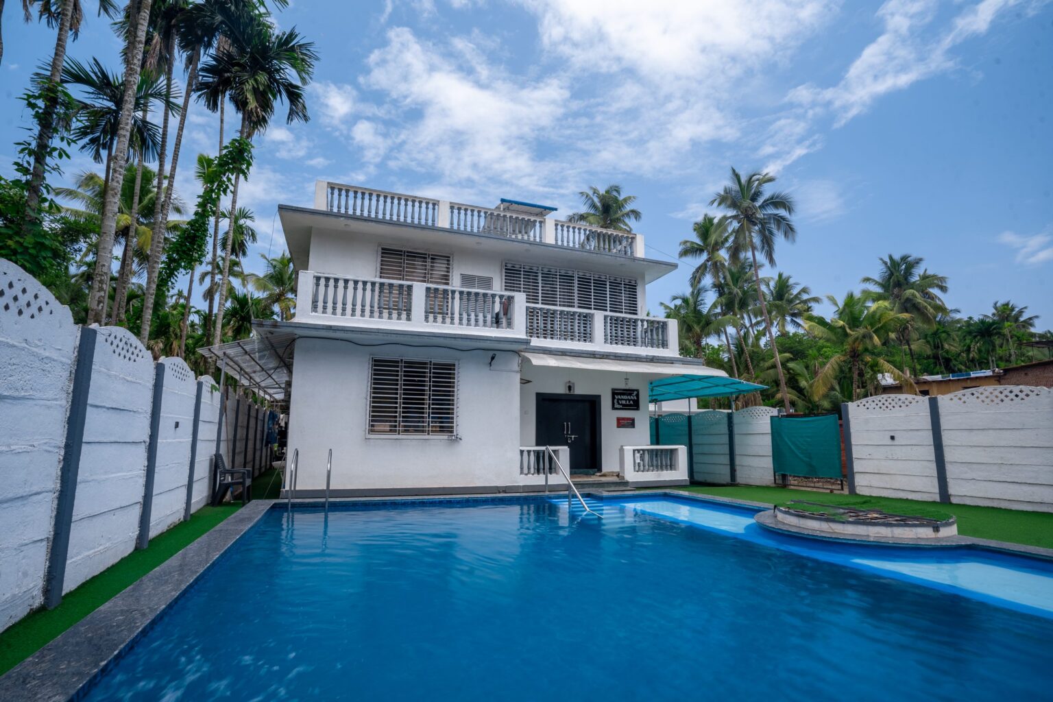 Vandana Villa, a white two-storey villa with a private pool and a turf lawn in Chaul, Alibag